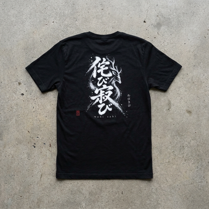 UTSURI WABI SABI (侘び寂び) t-shirt laid flat — the phrase wabi-sabi with a deer hidden in the brushstrokes across the back